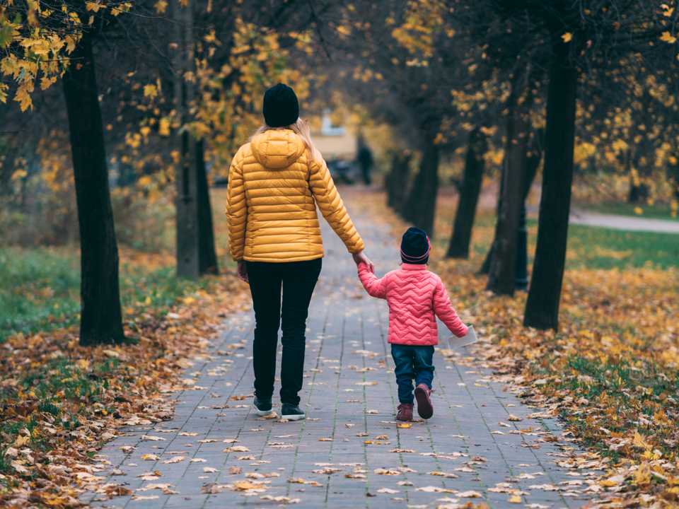 Une femme qui marche en touchant un petit enfant dans la main.